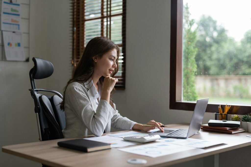 Woman accountant using calculator and computer in office, finance and accounting concept.